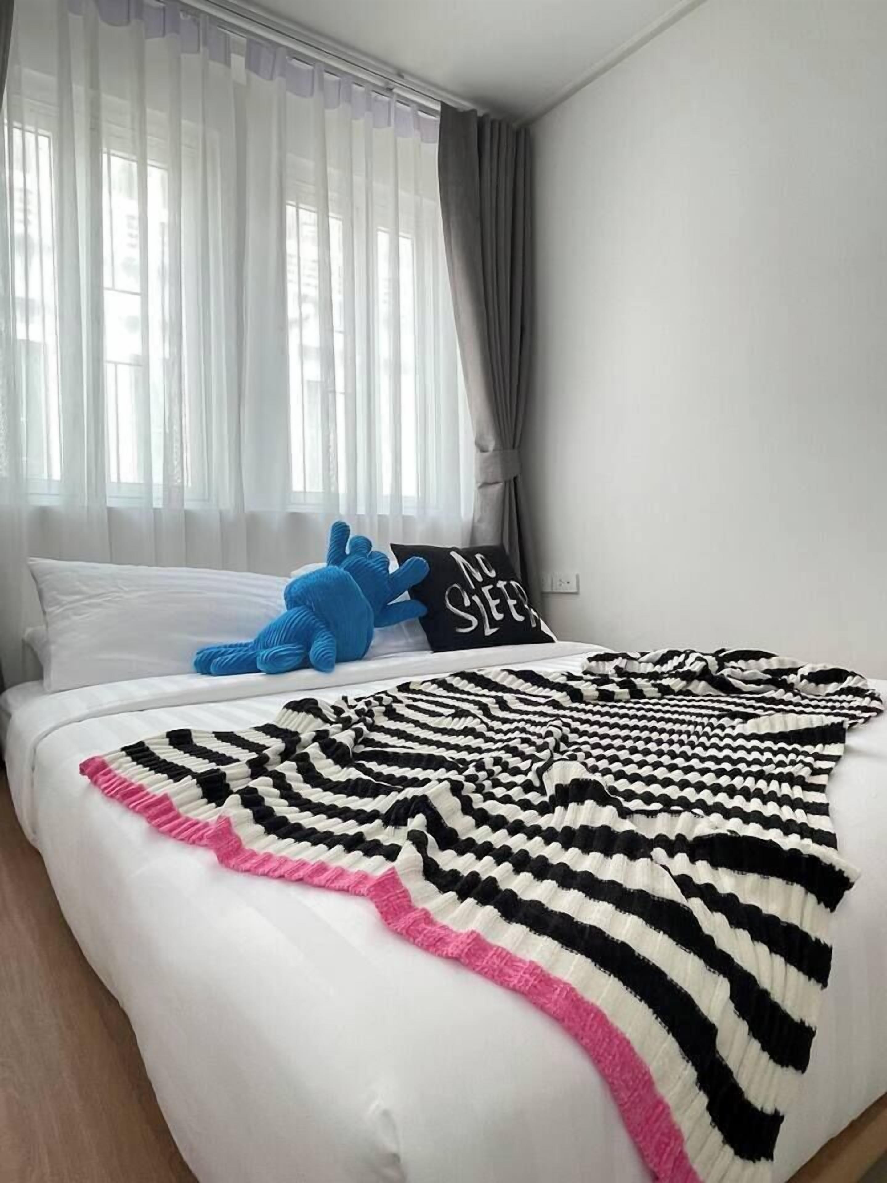 Une chambre à coucher avec un lit, une couverture, un oreiller et un jouet en peluche.