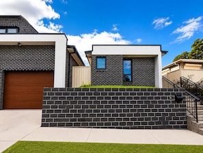 A modern residential building with a garage, a brick facade, and a small front yard. - Matilda’s Urban Escape | 6-Min Station & Shops (Bradbury)