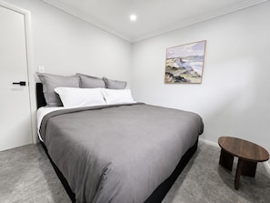A bedroom with a bed, a small table, and a painting on the wall. - Matilda’s Urban Escape | 6-Min Station & Shops (Bradbury)