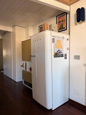 Ein weißer Kühlschrank mit einem Poster an der Tür, ein Holzschrank und eine Tür mit Griff.