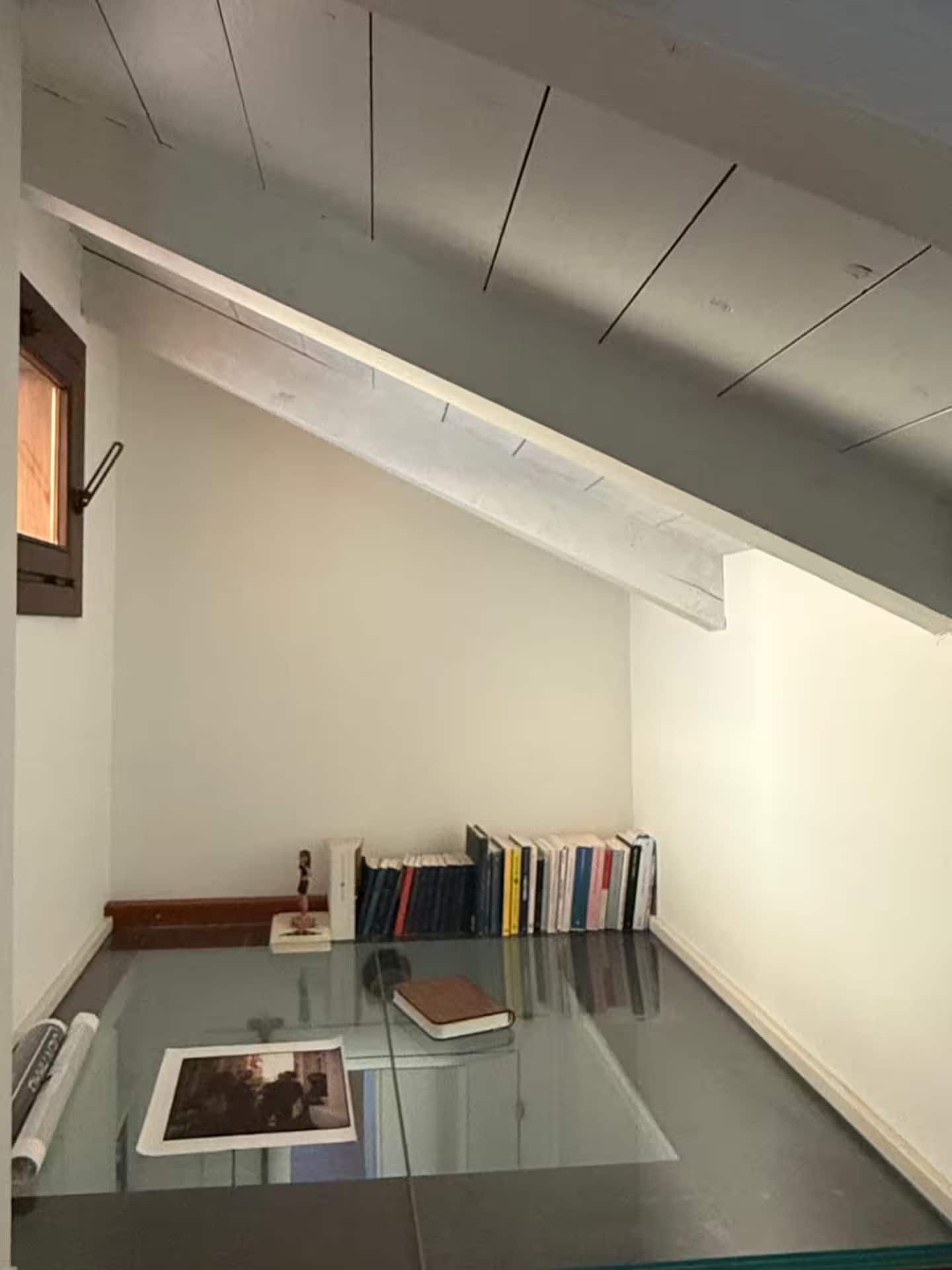 Una habitación con una mesa de vidrio, una estantería llena de libros y una puerta de madera.