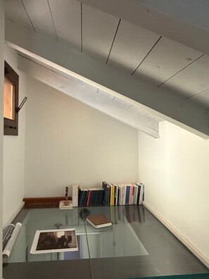 Ein Zimmer mit einem Glastisch, einem Bücherregal mit Büchern und einer Holztür.