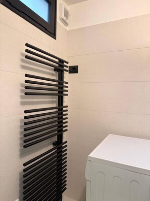 Ein Badezimmer mit einem schwarzen Handtuchhalter, einem weißen Heizkörper und einem gerahmten Bild an der Wand.