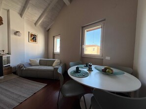 A cozy living area with a sofa, a dining table with chairs, and a kitchen area in the background. - Marvelous 1-bedroom apartment with AC in vibrant Cagliari (Cagliari)
