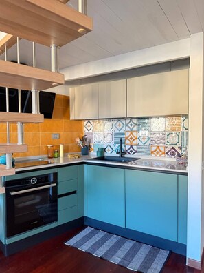 A modern kitchen with a built-in oven, a sink, and a backsplash with colorful tiles. - Marvelous 1-bedroom apartment with AC in vibrant Cagliari (Cagliari)