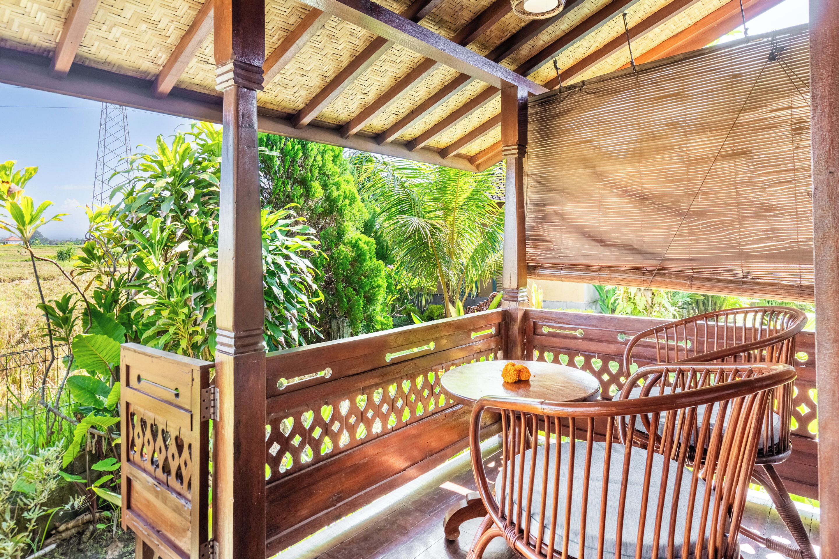 Una terraza de madera con una mesa y sillas, rodeada de abundante vegetación y vistas al paisaje.