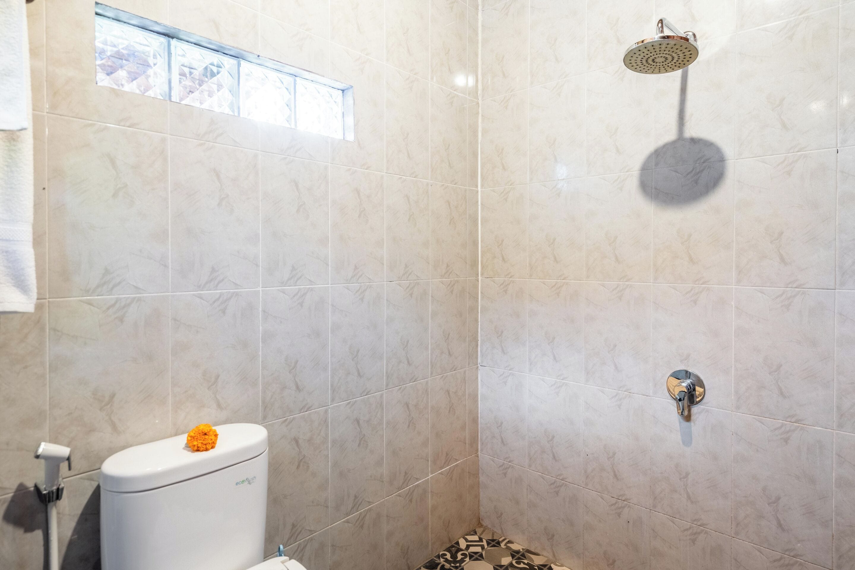 A bathroom with a toilet, a shower, and a window.