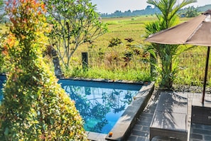 A swimming pool with a view of a green field and a fence. - Moonloka Eskabbe Maha Villa (Gianyar)
