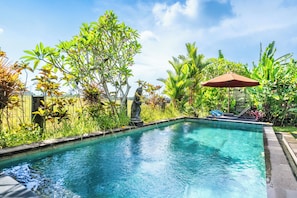 A swimming pool surrounded by lush greenery and a statue. - Moonloka Eskabbe Maha Villa (Gianyar)