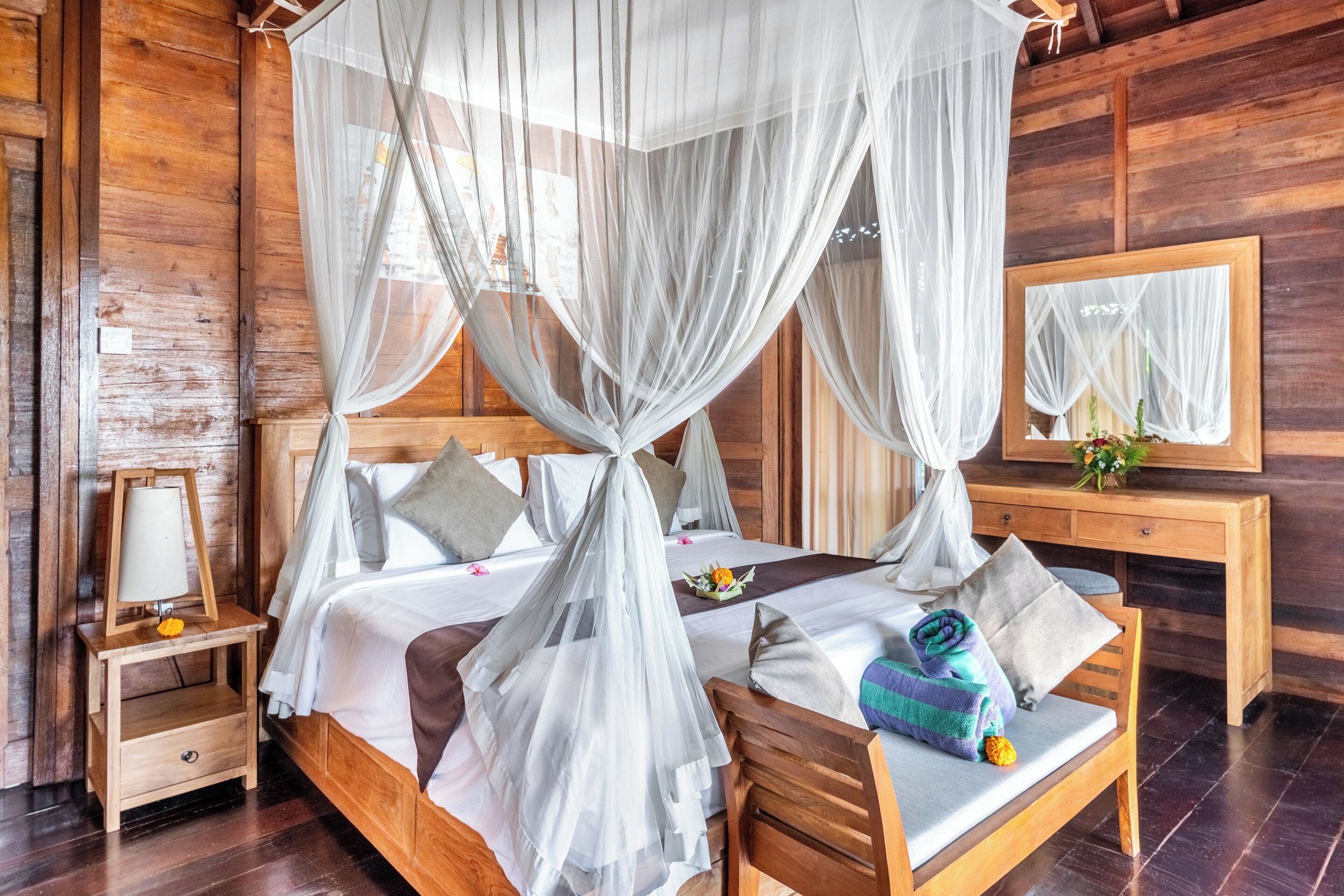 Una habitación de madera con cama con dosel, una mesita de noche, un espejo y una mesilla.