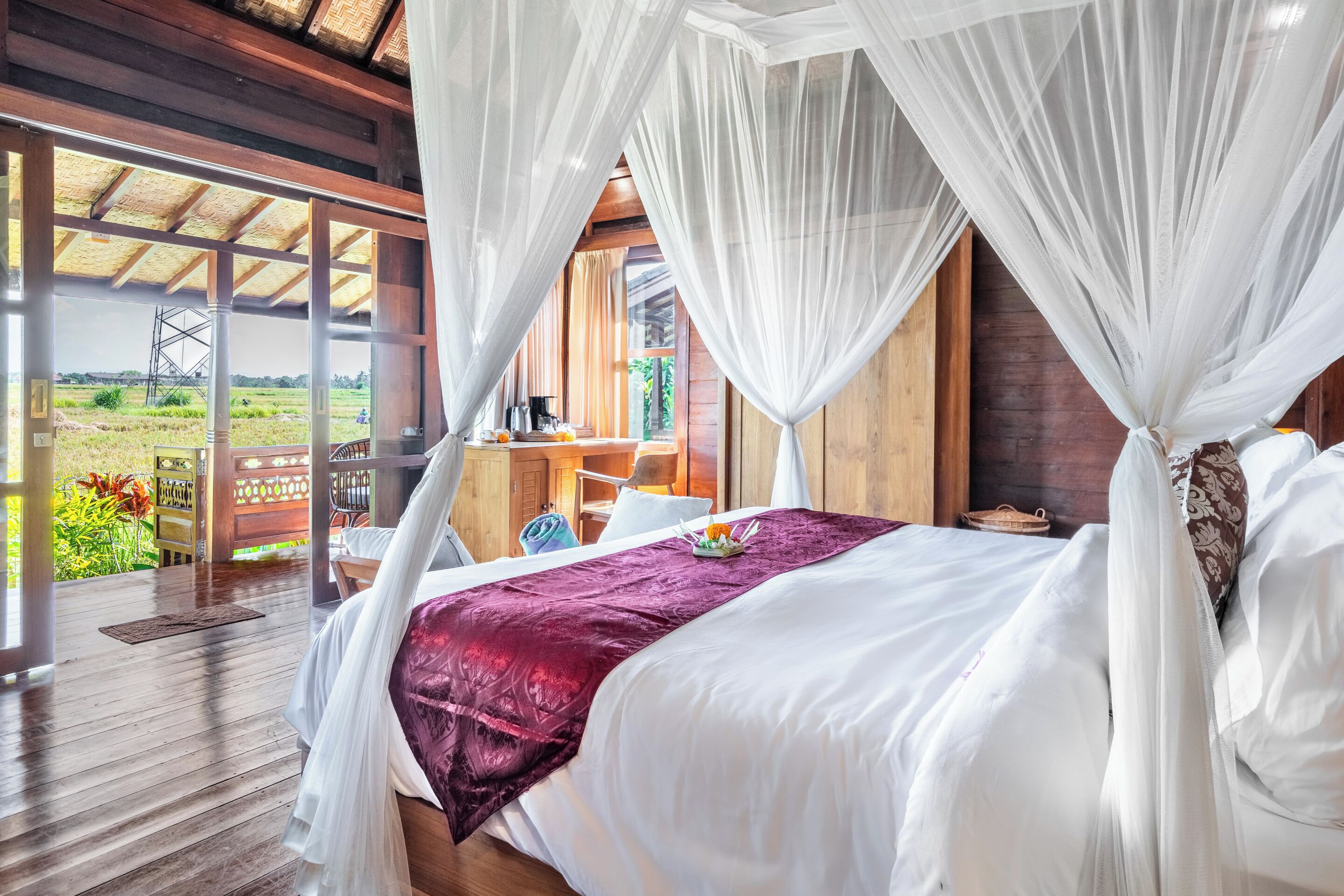 Un dormitorio con cama a dosel, suelo de madera y vistas a un paisaje rural.