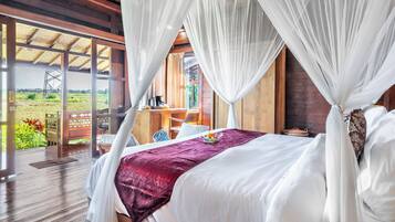 Un dormitorio con cama a dosel, suelo de madera y vistas a un paisaje rural.