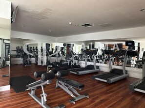 Ein Fitnessraum mit Cardiogeräten, Gewichten und Spiegeln.