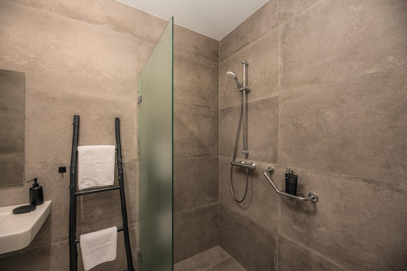 A modern bathroom with a glass shower door, a towel rack, and a sink.