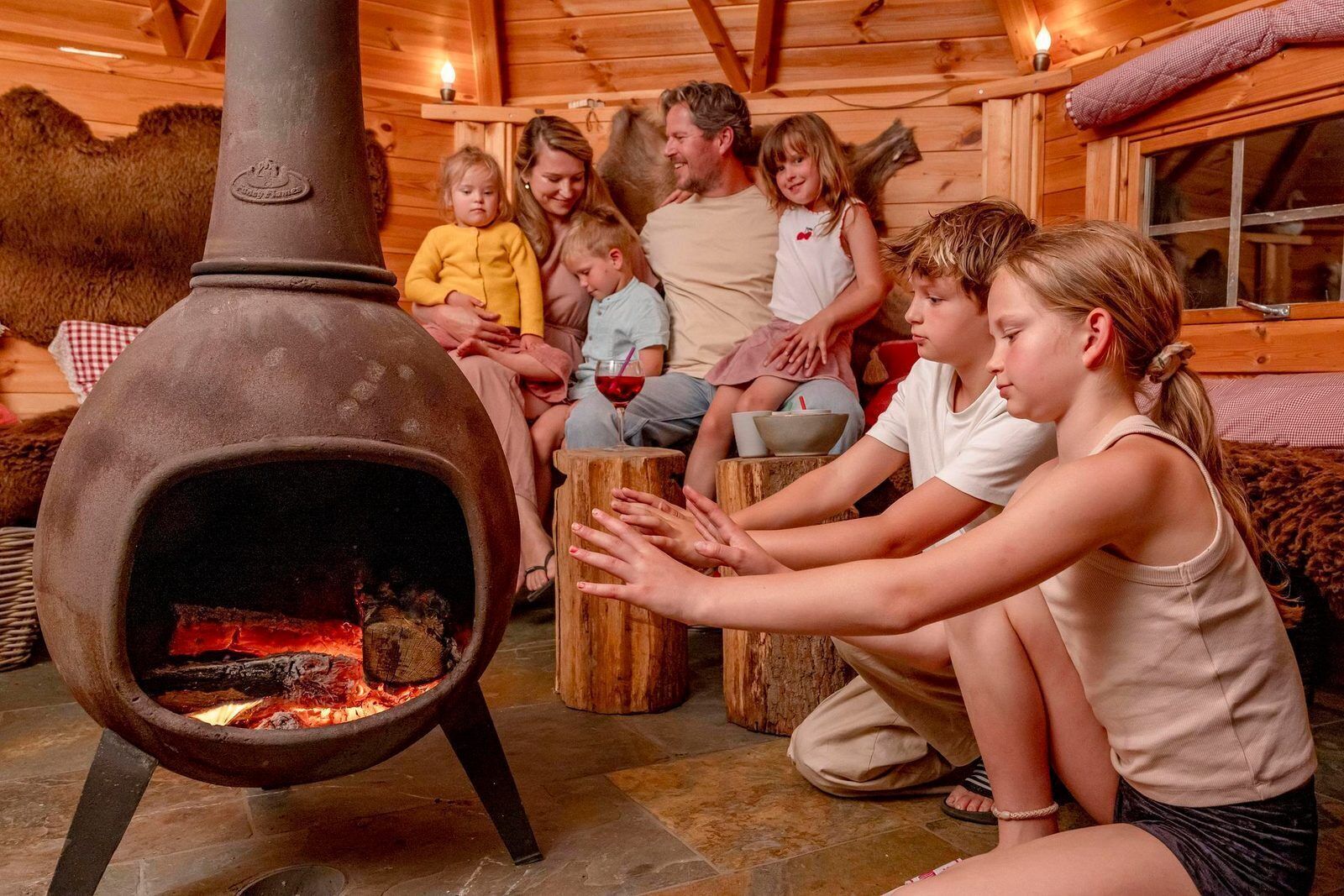 En familj hade samlats runt en vedeldad kamin i en rustik stuga med träväggar och ett stengolv.