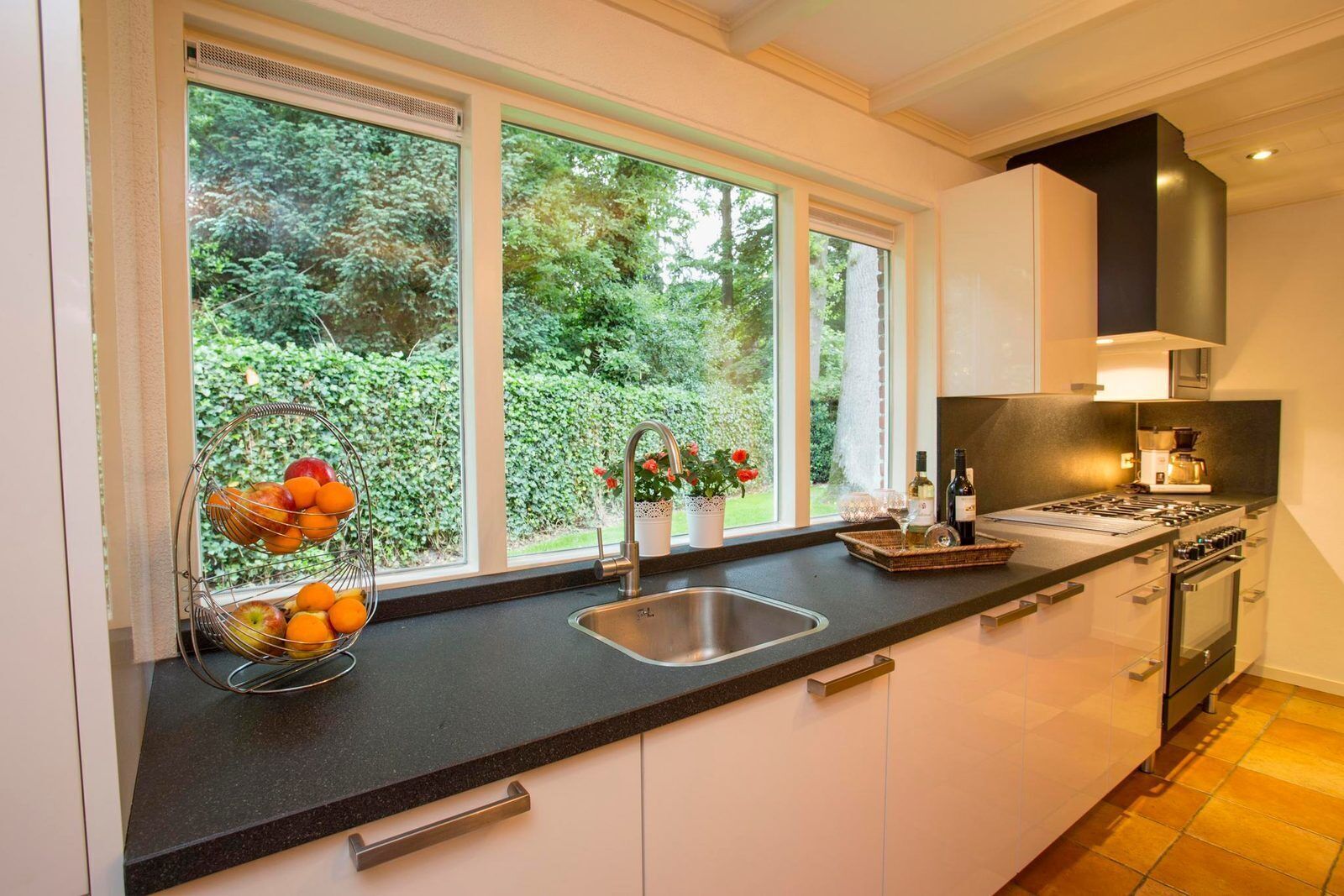 A modern kitchen with a black countertop, stainless steel sink, and a gas stove.