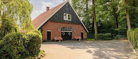 A traditional wooden house with a sloped roof, a brick facade, and a paved driveway.