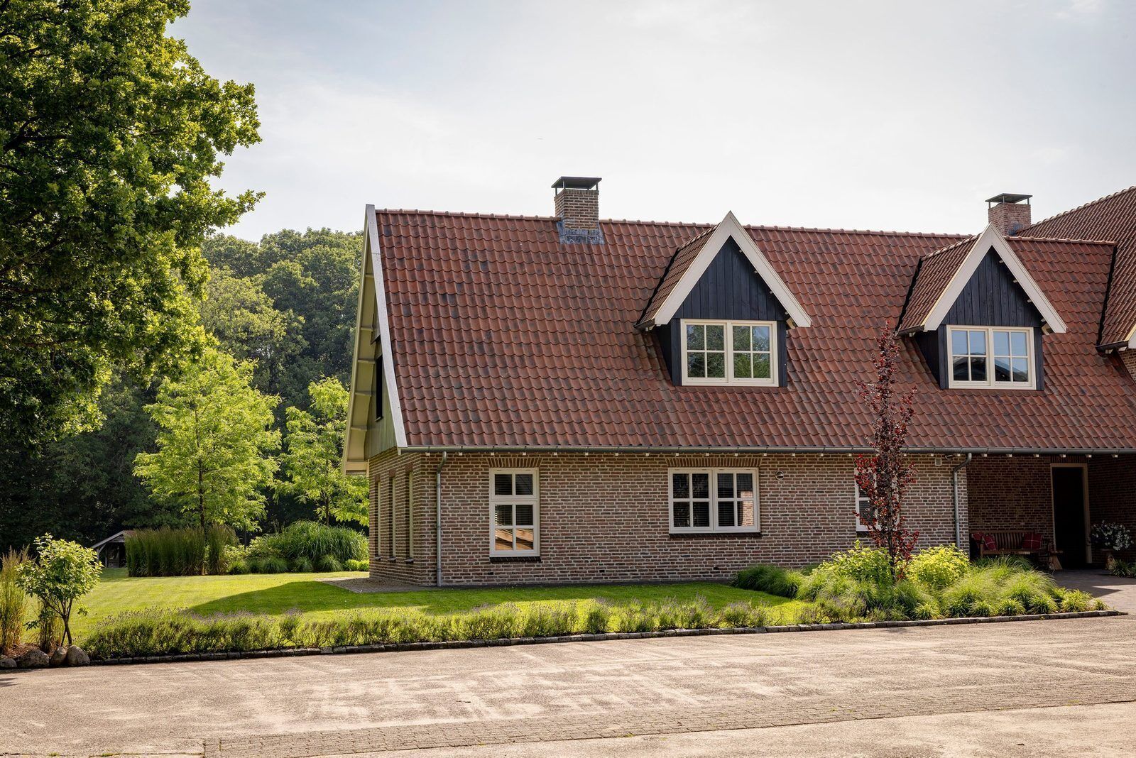 Une maison à deux étages avec une façade en briques, un toit en pente et une pelouse bien entretenue.