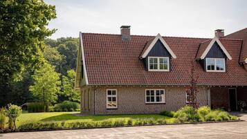 Een herenhuis met een bakstenen gevel, een schuin dak en een verzorgd gazon.
