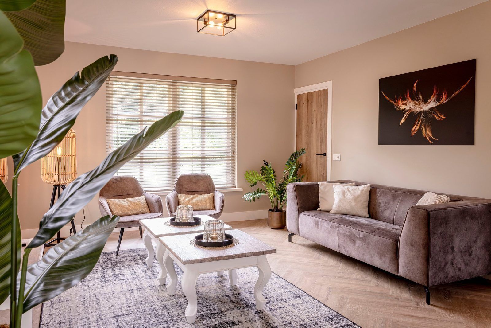 Een woonkamer met een bank, twee fauteuils, een salontafel en een potplant.