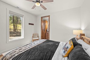 Een slaapkamer met een bed, een stoel, een houten deur en een raam.