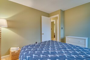 Un dormitorio con cama, mesita de noche, lámpara y cómoda.