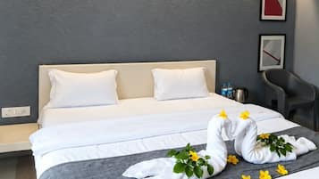A modern hotel room with a large bed, a bedside table with a lamp, and a wall-mounted artwork.