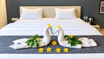 A neatly made bed with white linens and a decorative towel swan centerpiece.