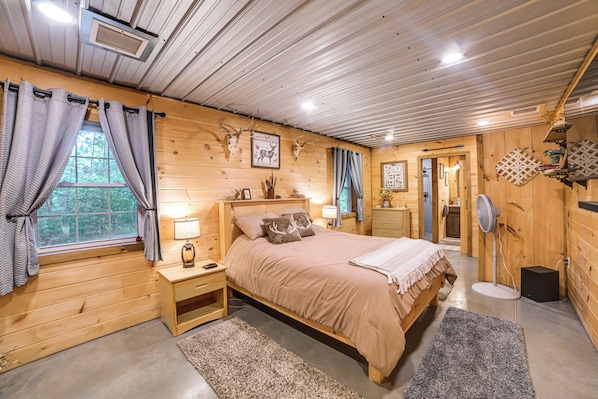 A wooden cabin bedroom with a bed, nightstands, a lamp, and a fan. - Only Minutes From Kentucky Lake, Fish & Relax! (Murray)