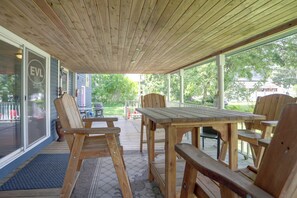 A wooden deck with a table and chairs, a covered area with a view of the outdoors, and a building with a sign that reads 'EVL'. - Downtown Spacious 5BR w/ Game Room (Ellicottville)