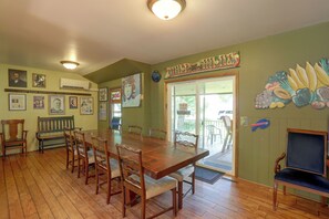 Un coin repas avec une table et des chaises en bois, une grande fenêtre offrant une vue agréable et divers éléments de décoration murale, notamment des tableaux et des panneaux encadrés.