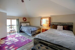 Une chambre avec deux lits, une tête de lit en bois, une fenêtre avec des rideaux, un plancher en bois et une porte donnant sur un balcon.