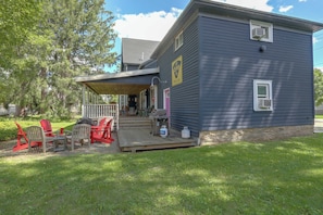 A two-story house with a porch, outdoor seating, and propane tanks.