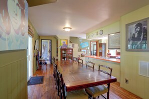 A dining area with a long wooden table, chairs, and a kitchen counter. - Downtown Spacious 5BR w/ Game Room (Ellicottville)