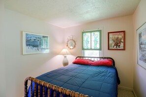 A bedroom with a bed, a lamp, a window with a wreath, and framed pictures on the wall. - Carley House Too: Pet Friendly, Hot Tub, Fire Pit! (Little Valley)
