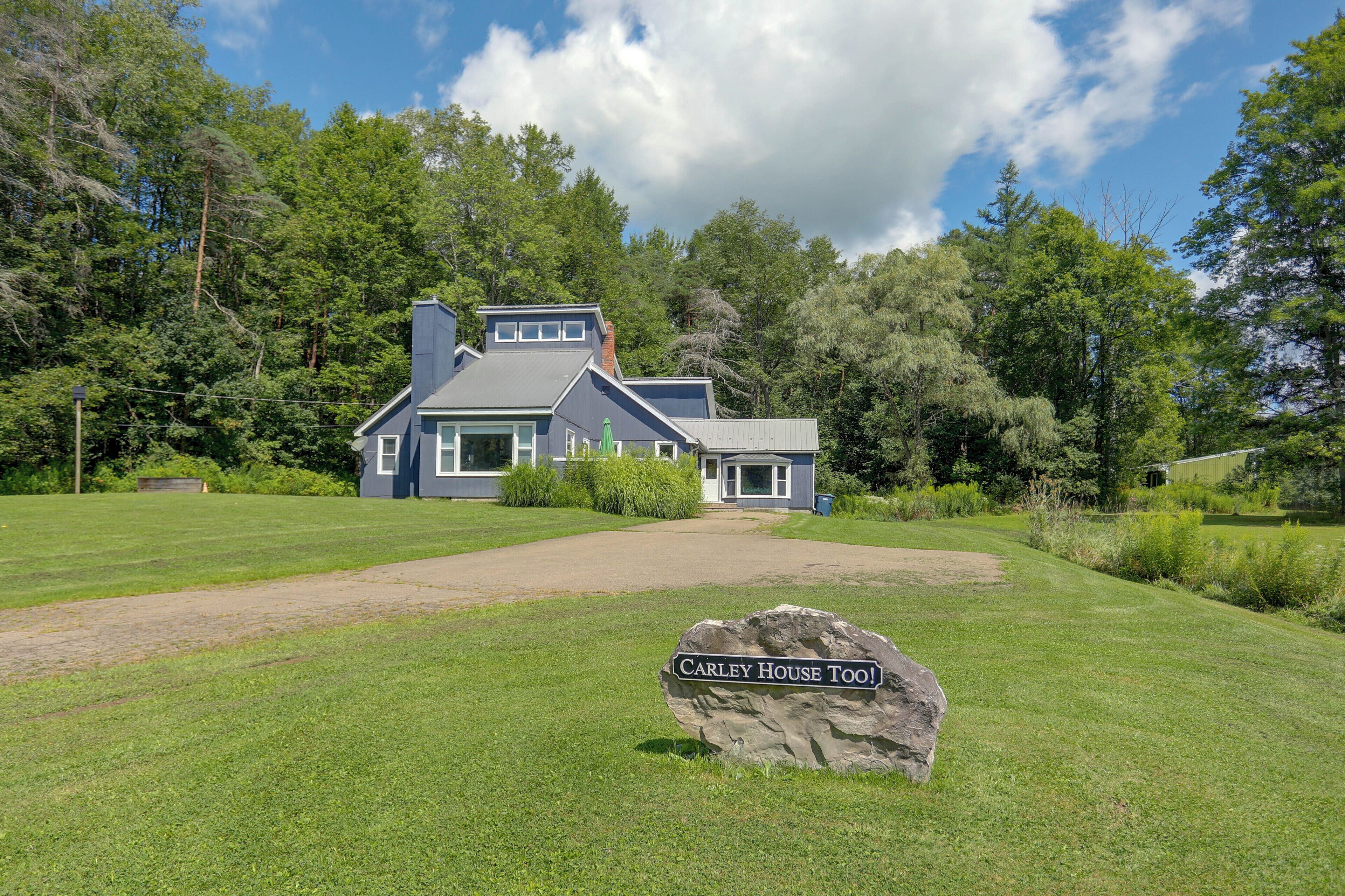 Une maison à deux étages avec une enseigne en pierre devant.