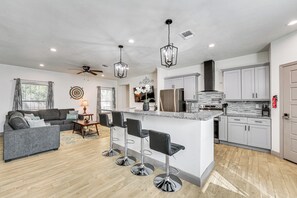 A modern kitchen with a central island, bar stools, and a ceiling fan. - Walk to Parks & Dining! Universal City Home (Universal City)