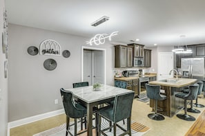 A modern kitchen with a central island, bar stools, and a dining table with chairs. - Extended Stay Gem Near Redstone Arsenal & Airport (Madison)