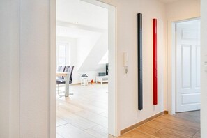 Ein Flur mit einer weißen Tür, einer weißen Wand und einem Holzboden.