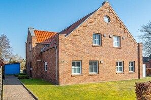 Ein Ziegelhaus mit Satteldach, Garage und gepflegtem Rasen.