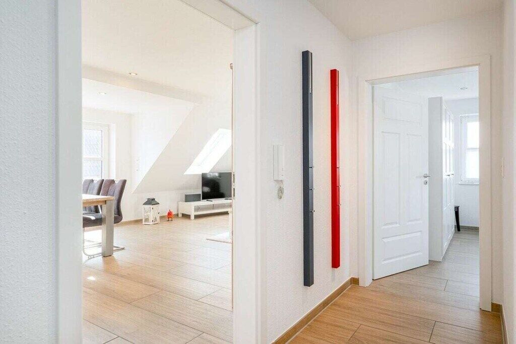A modern interior with a dining area, a living space with a TV, and a staircase.