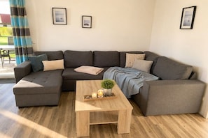 Un saló modern amb un sofà modular, una taula de centre de fusta i dos quadres emmarcados a la paret.