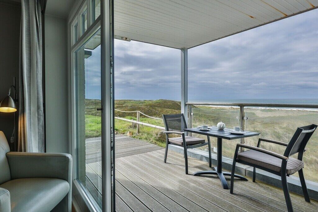 Un espace extérieur abrité, avec une table et des chaises, donnant sur un paysage verdoyant.