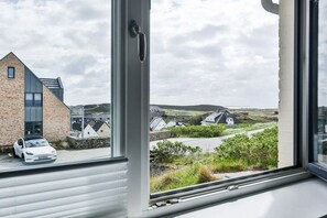 A modern building with a large window, a parked car, and a view of a rural landscape. - Holiday apartment with 3 bedrooms (Hörnum \/ Sylt)