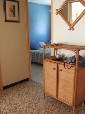 Ein Zimmer mit einem Bett, einem Korbschrank und einem Spiegel an der Wand.