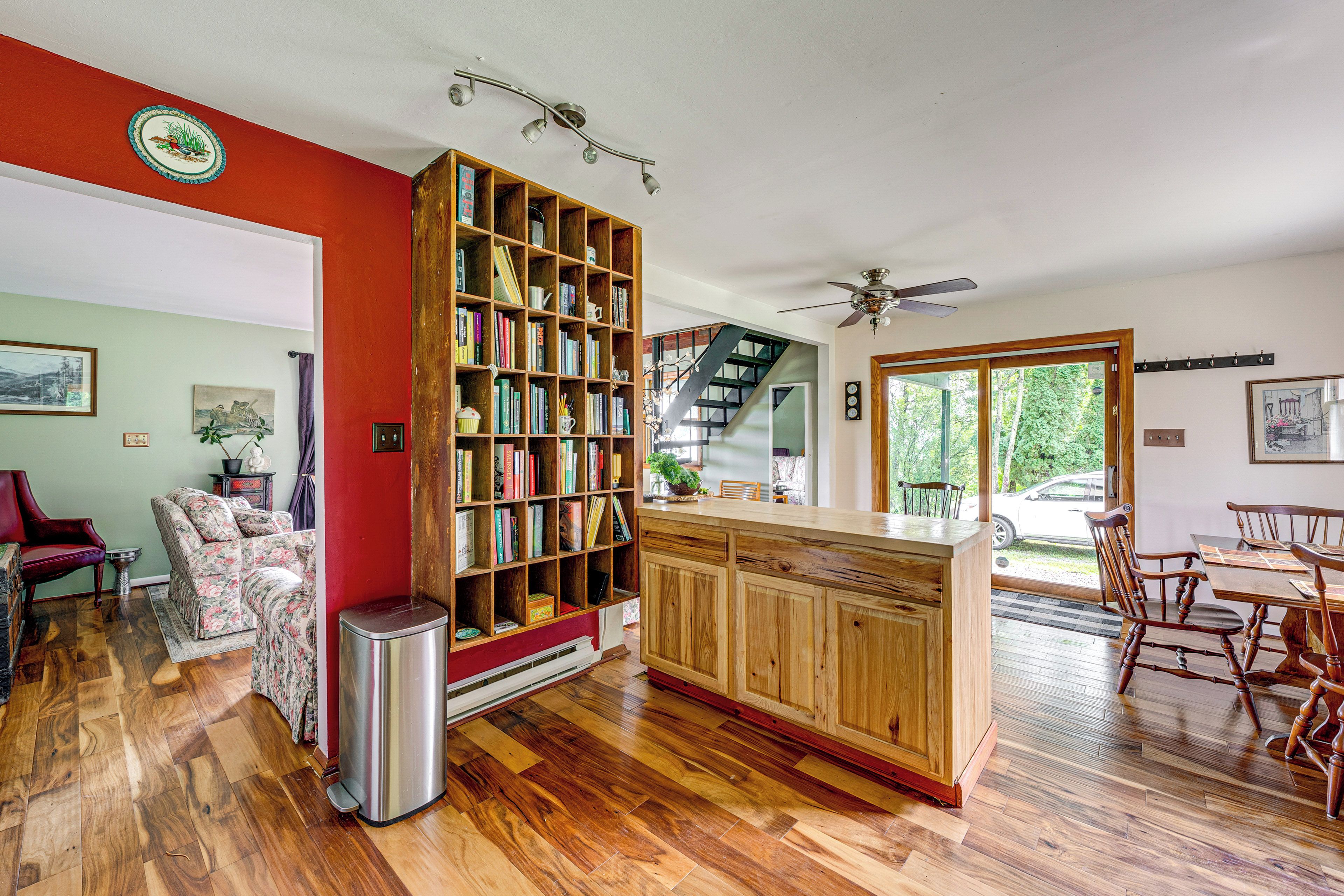 Une cuisine spacieuse avec une bibliothèque en bois, un coin repas comprenant une table et des chaises, et un escalier menant à un autre niveau.