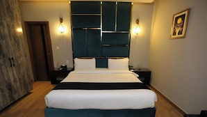 Une chambre moderne avec un grand lit, deux tables de chevet, une tête de lit ornée de motifs géométriques et des luminaires fixés au mur.