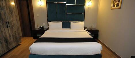 A modern bedroom with a large bed, two bedside tables, a headboard with geometric patterns, and wall-mounted lighting.