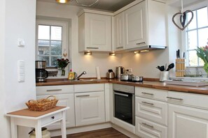Een keuken met witte kastjes, een houten aanrecht, een fornuis en een raam met uitzicht.