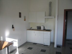 Una kitchenette pequeña con microondas, lavamanos y armarios.